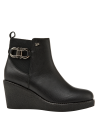 Botín chelsea negro de mujer en cuero con suela de cuña, estilo casual y urbano, con detalle metálico decorativo.