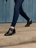 Zapato de mujer negro en cuero charol con diseño moderno y elegante, acabado de piel de reptil, ideal para estilo urbano.