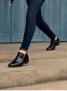 Zapato de mujer negro en cuero charol con diseño moderno y elegante, acabado de piel de reptil, ideal para estilo urbano.