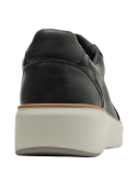 Zapatilla negra de cuero con ojales dorados y suela blanca, combinando deportividad y sofisticación.