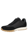 Zapatilla negra deportiva de mujer con diseño minimalista y detalles en suela café claro.