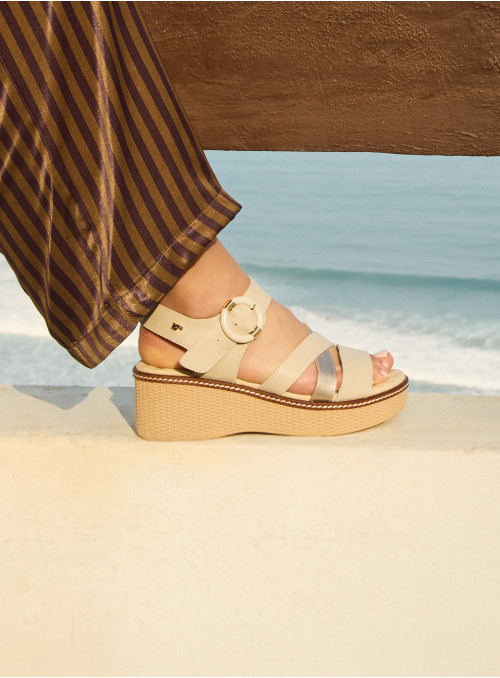 Versátil sandalia de cuero beige para mujer, complemento ideal con bolso de rafia.
