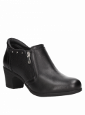 Cuero negro en botín casual de mujer, estilo urbano con remaches y relieve reptil, versátil para cualquier atuendo informal.